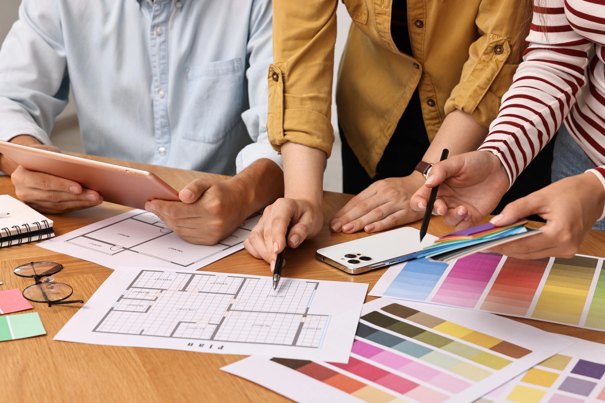 People collaborating on a design project with floor plans and color swatches.