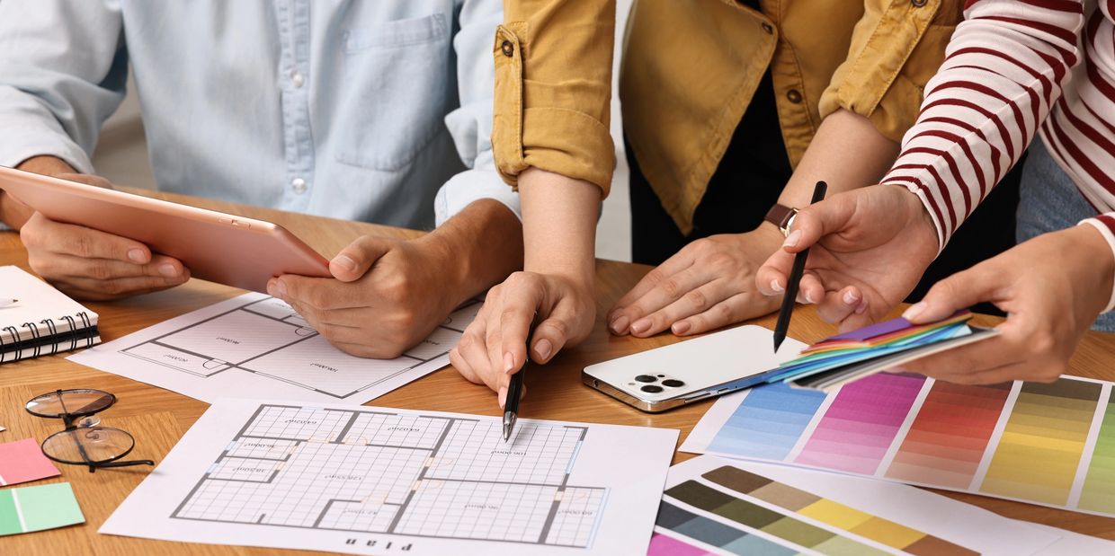 People discussing floor plans and color swatches at a table.