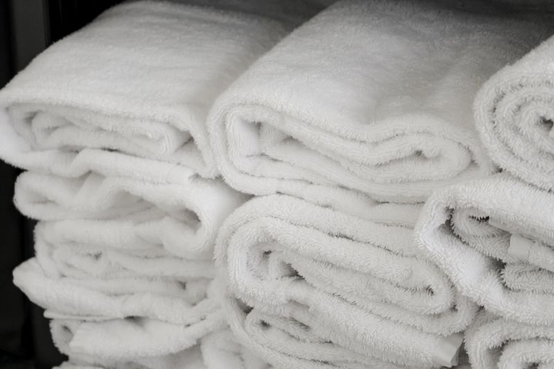 an arrangement of folded white bath towels on a shelf. hotel, spa, home, gym, or well-organized linen closet. clean organization background