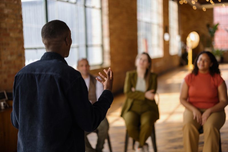 Business coach is leading a workshop with a diverse group of professionals in a modern office space