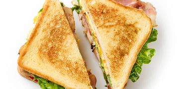 Two toasted club sandwich halves with lettuce and bacon.