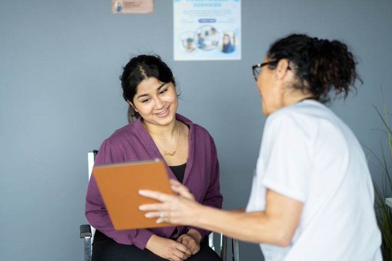 A doctor discusses health records with a patient during a professional medical consultation in a comfortable office setting. The patient appears engaged and focused, ensuring quality communication and care.