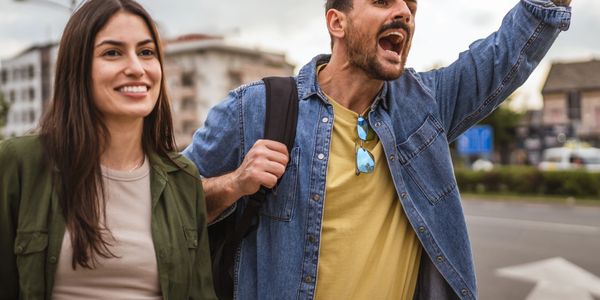 Young couple happily hailing a taxi on a city street.