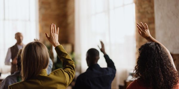 People raising hands in a meeting or class.