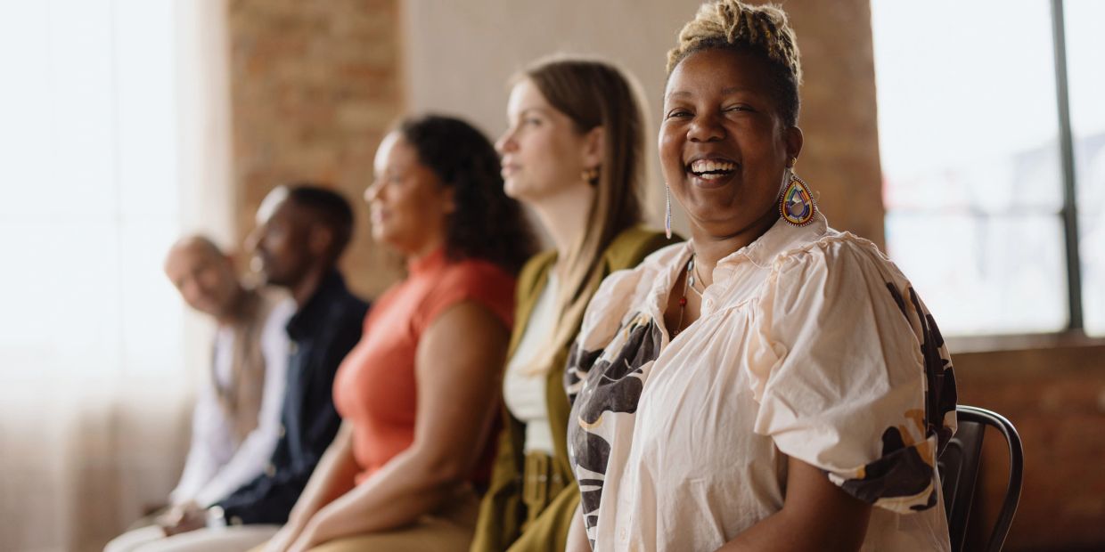 Diverse group seated with a joyful woman smiling at the camera.