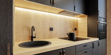 Modern kitchen with black cabinets and light wood countertops.