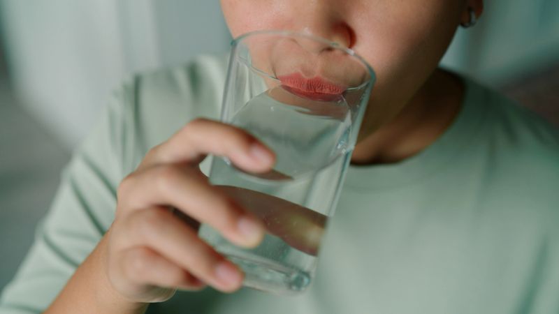 Asian woman drinking water from glass at home