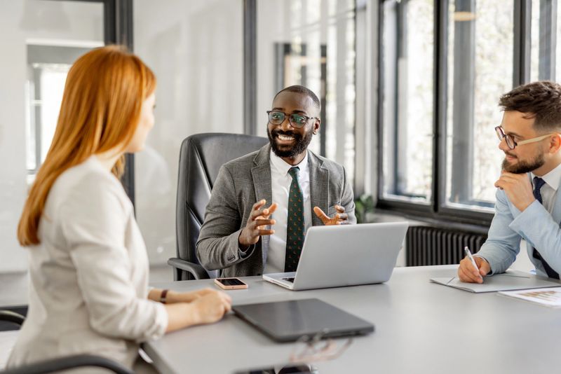 A smiling professional shares innovative ideas during a collaborative meeting, showcasing the spirit of teamwork and creativity in an office setting.