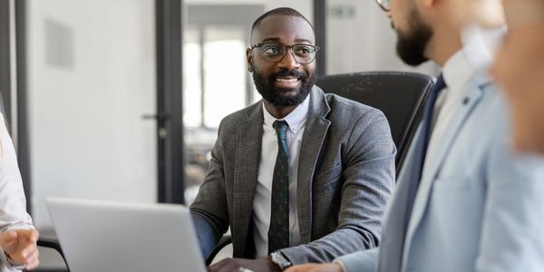 Business professionals in a meeting, discussing work with a laptop.