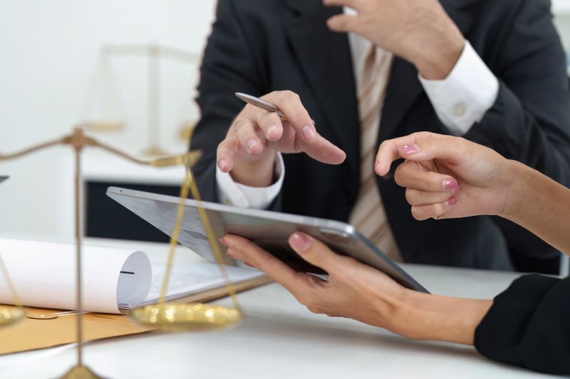 A lawyer provides expert advice to a client while reviewing legal documents on a tablet, showcasing the importance of technology in legal consultations.