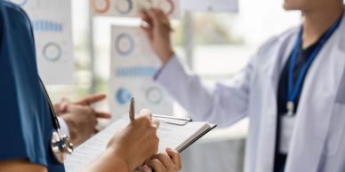Medical professionals discussing data with clipboard notes.