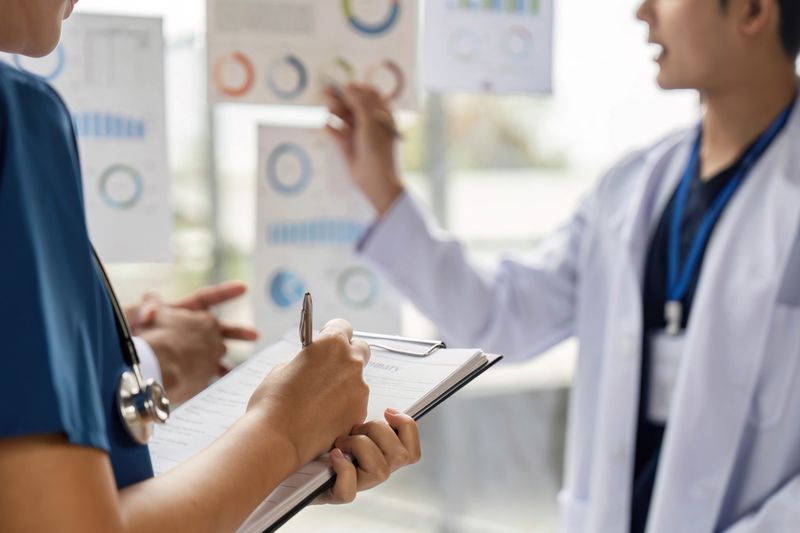 A group of doctors analyzing charts and discussing patient data in a collaborative medical environment, showcasing teamwork and patient care.