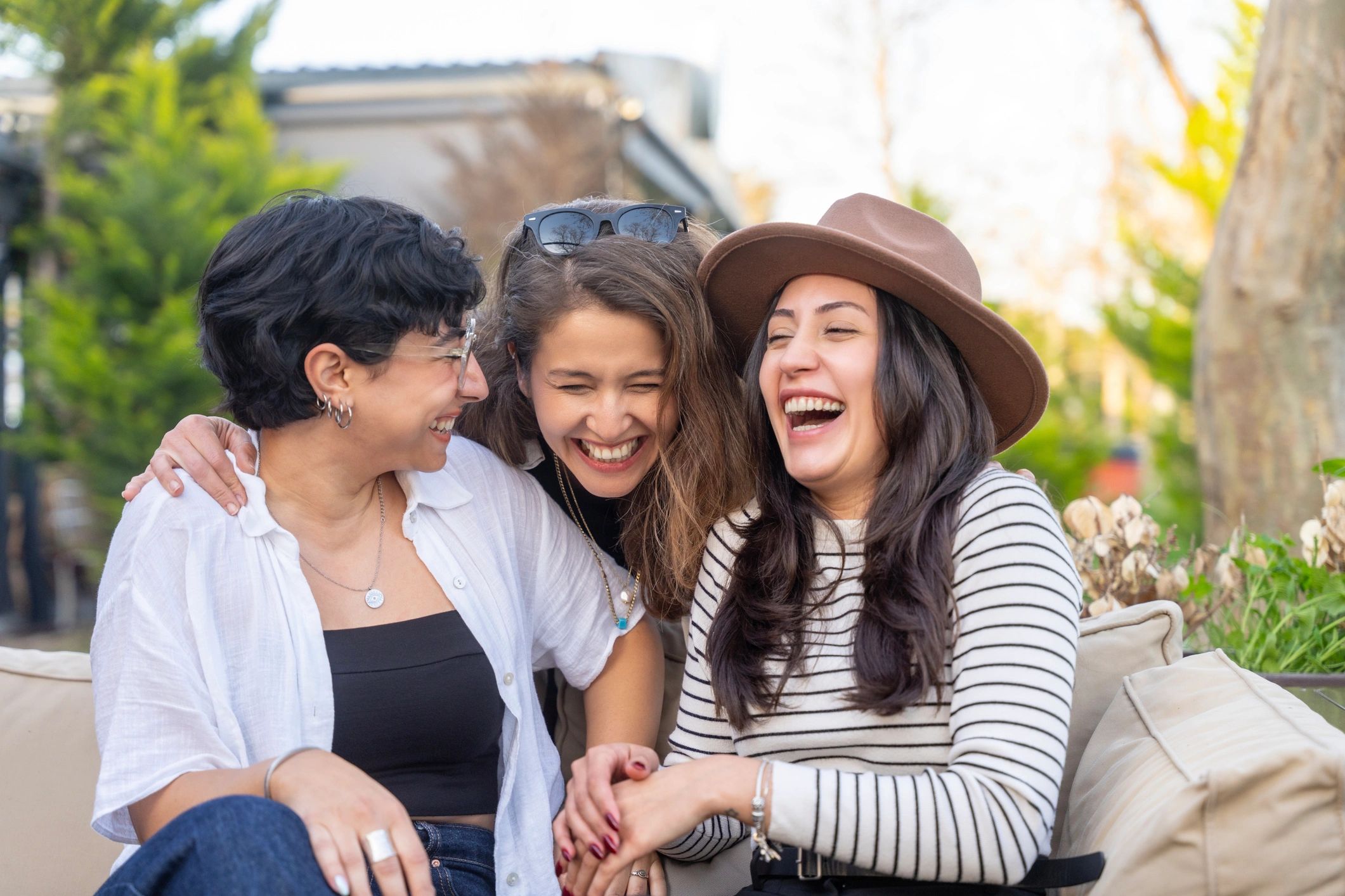 Three women sitting together outdoors, laughing and enjoying a conversation.