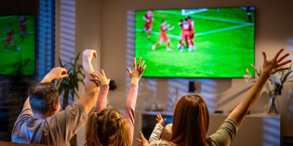 Une famille regarde un match de foot à la télévision.