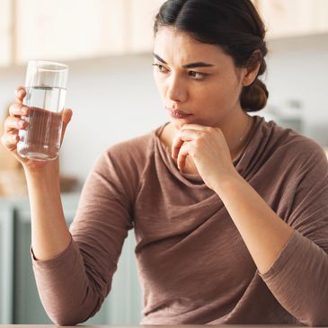 Woman suspiciously looking at a glass of water.