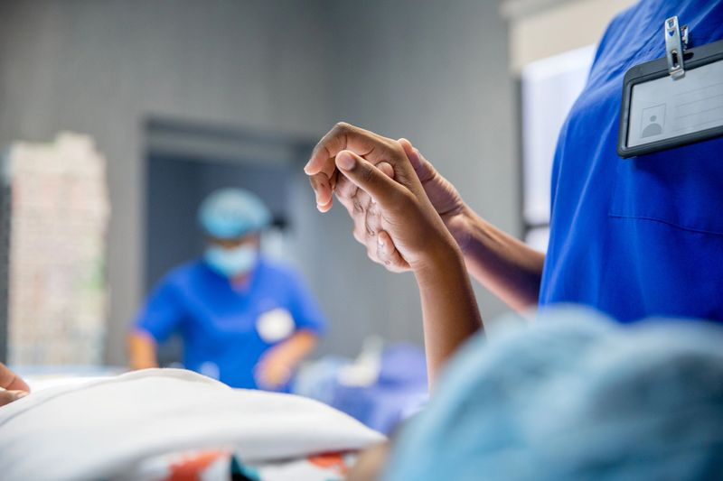 Female anaesthesiologists holding a young patient hand