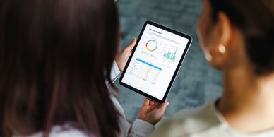 Two people reviewing data on a tablet.
