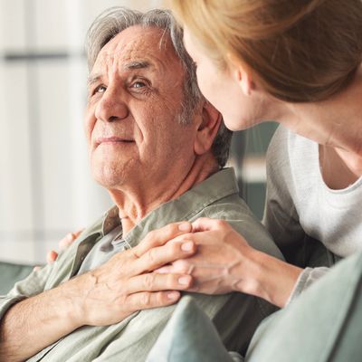 A woman comforting an elderly man with a caring touch on his shoulder.