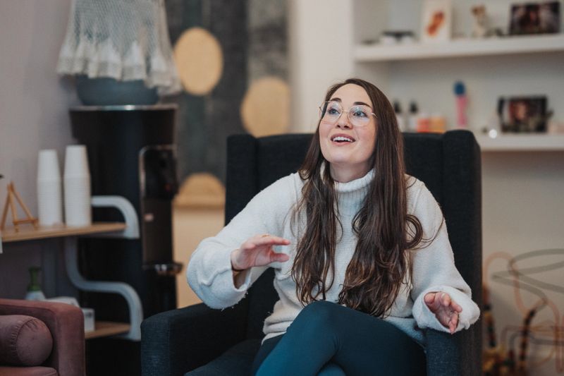 A doctor of physical therapy who specializes in pregnancy, postpartum, and infant development, and is also a certified lactation consultant, sits in an armchair and leads a support group and parent education class for new moms.