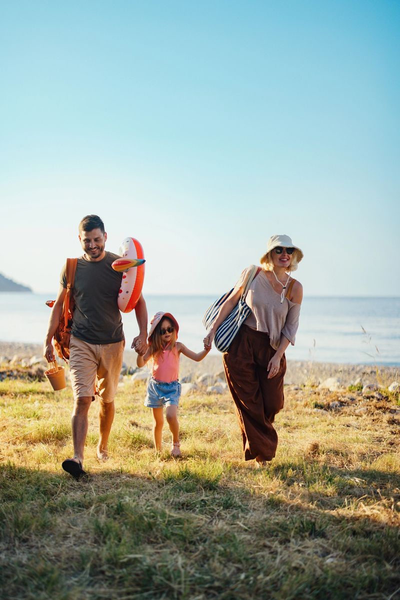 A cheerful family walks together on a beach during their summer vacation, enjoying fun and sunshine by the seaside. The joyful atmosphere captures a special bonding moment in a picturesque coastal setting.