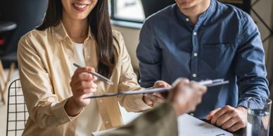Young couple happily signing documents in a cozy office setting.