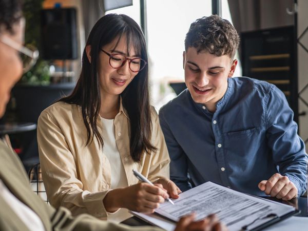 A young couple signing paperwork with a professional advisor.