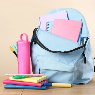 Blue backpack with school supplies on table.