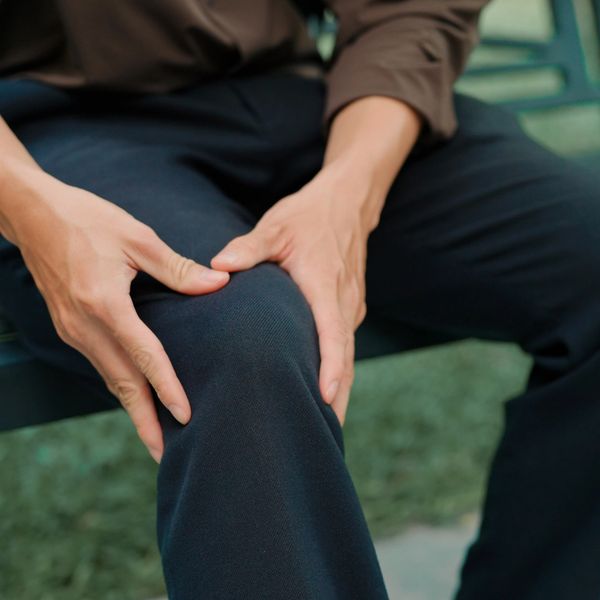 Person holding their knee in apparent discomfort while sitting.