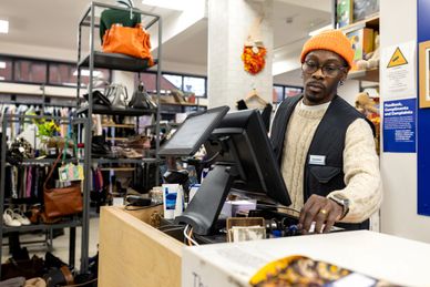 A man working at a retail store checkout counter.