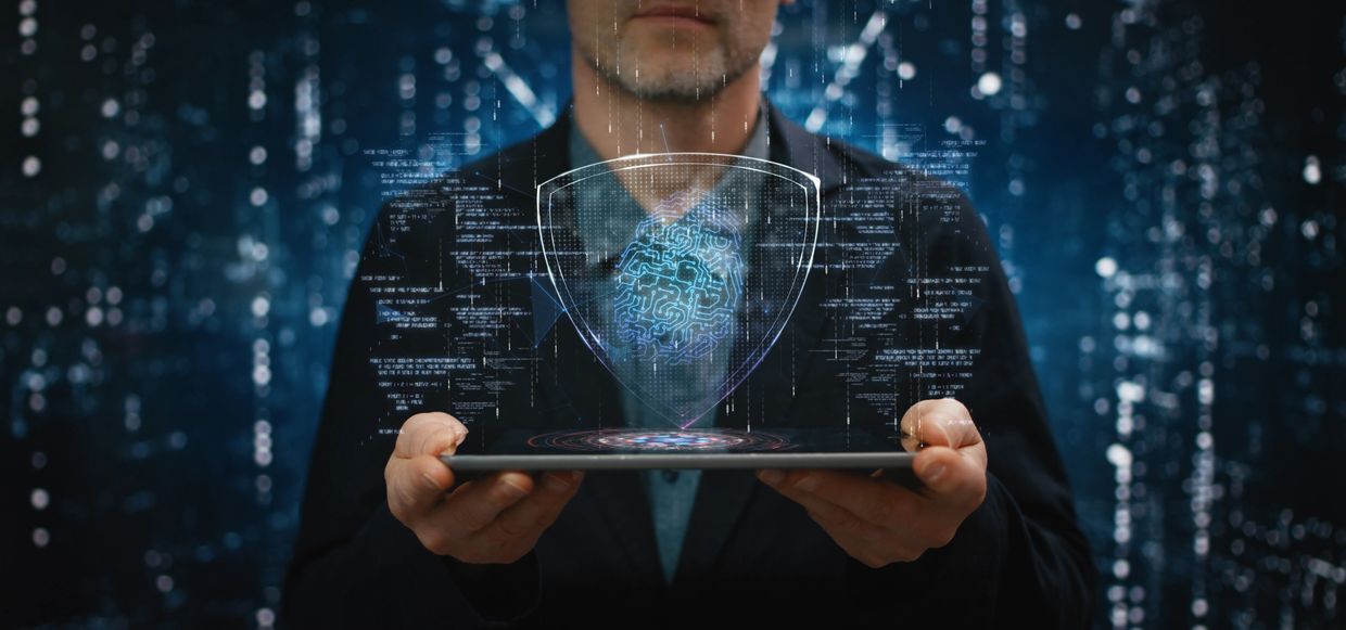 Man holding tablet with digital fingerprint and shield hologram.