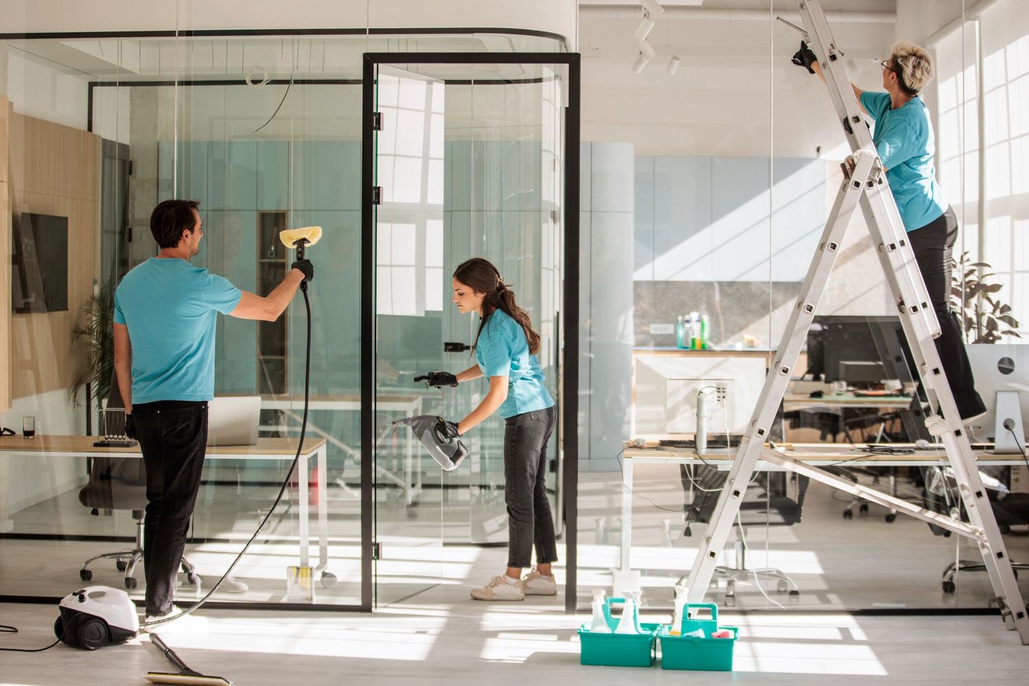 Three people cleaning an office space.