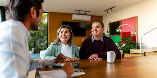 Couple smiling during a meeting with a professional at a wooden table.