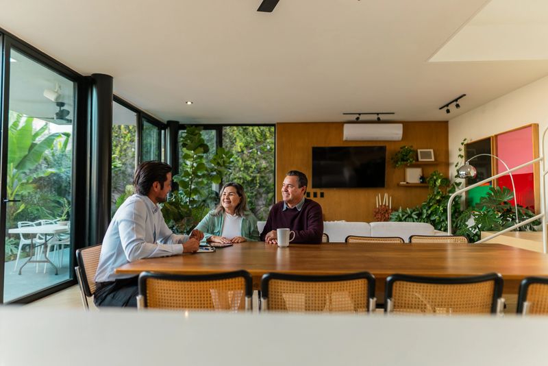 Senior couple talking to real estate agent at house