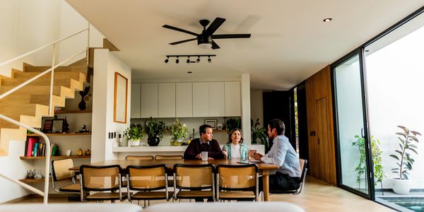 Three people having a conversation at a dining table in a modern home.