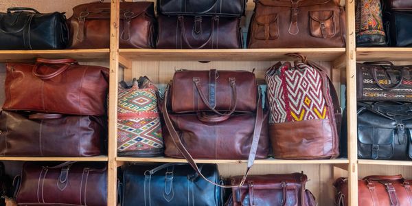 A variety of leather and patterned bags displayed on wooden shelves.