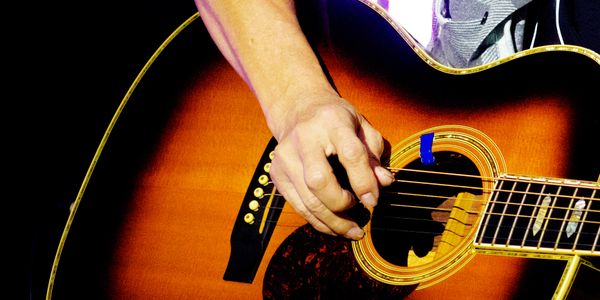 Close-up of a hand strumming an acoustic guitar.