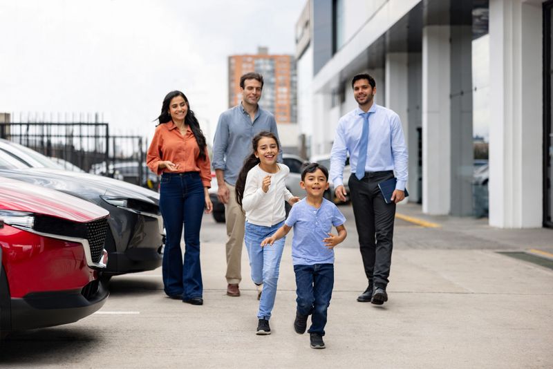 Excited Latin American family buying a car and kids running at the dealership and smiling