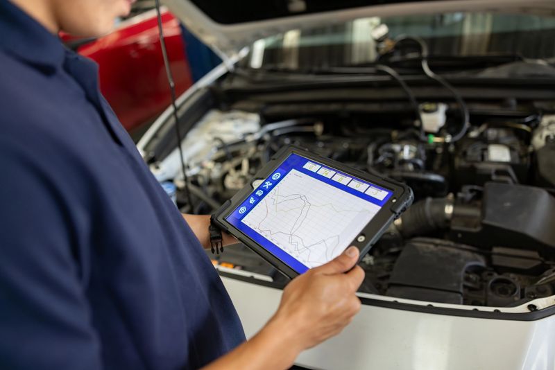 Close-up on a mechanic using a scanner to diagnose a problem with a car at the garage