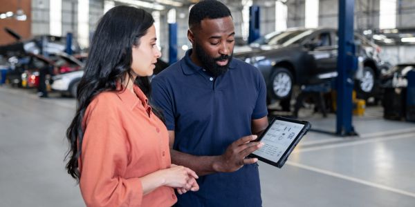 Two people discussing a repair order in a car workshop.