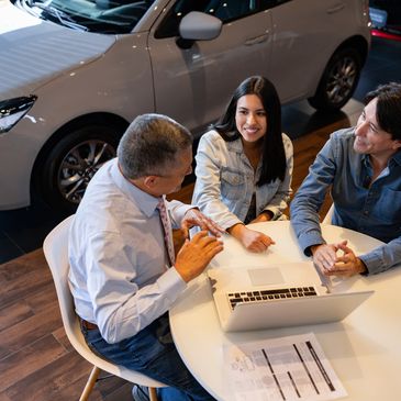 People discussing car purchase details at a dealership.