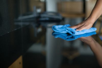 Hand cleaning a black surface with a blue cloth.