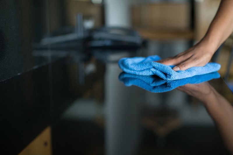 Dusting the shiny surface of a hotel desk with a microfiber towel