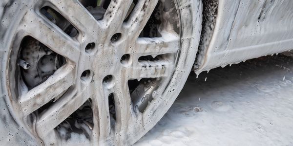 Car wheel covered in foam during washing.