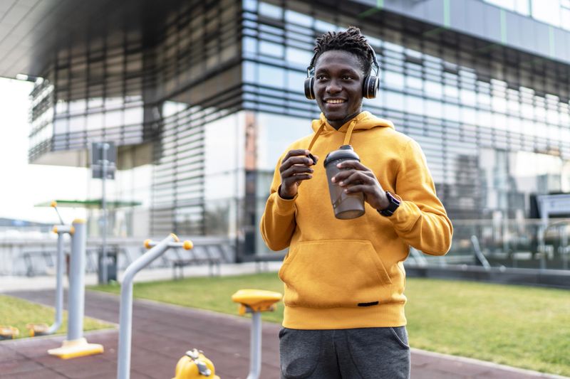 Smiling african american sportsman enjoying a protein shake after an invigorating outdoor workout in a calisthenics park, embracing a healthy and active lifestyle