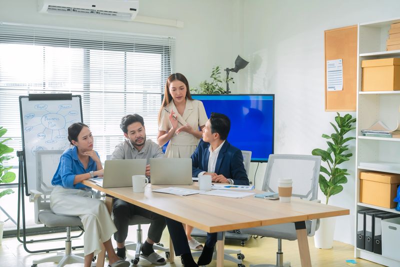 Asian business team standing together in modern office, brainstorming ideas while looking at a large digital screen, teamwork, strategy, innovation, collaboration orporate teamwork, planning, digital