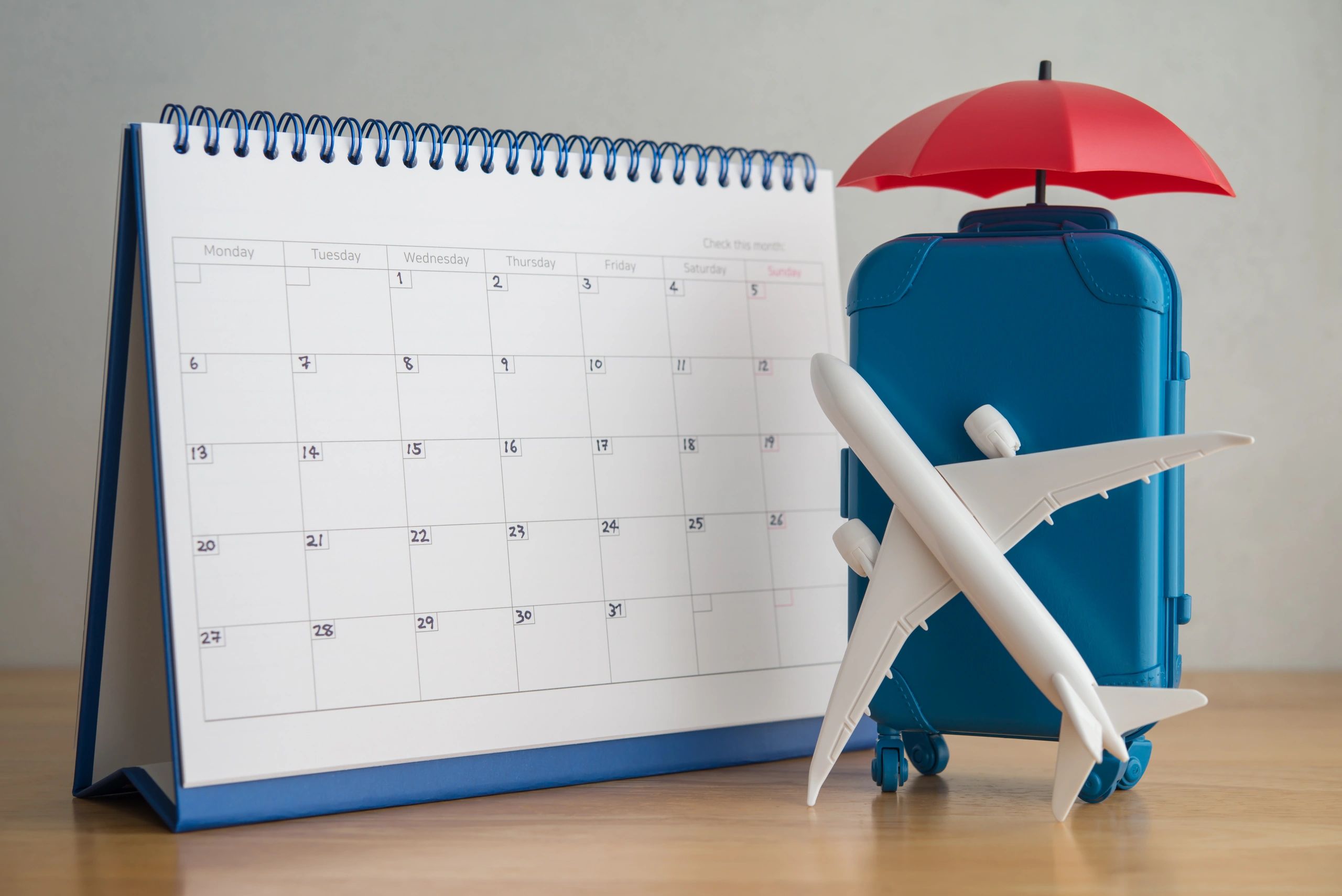 Calendar with travel-themed items including suitcase, airplane, and umbrella.