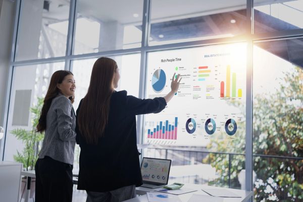 Woman analyzing charts on a large touchscreen display in office.