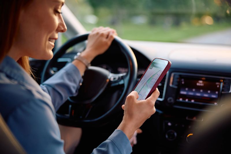 Close up of woman using navigation software on mobile phone on a road trip.