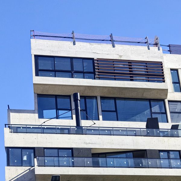 Modern concrete building with glass balconies under a clear blue sky.