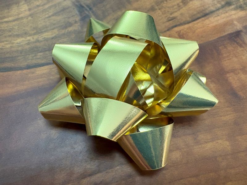 Gold colored shiny satin ribbon, tied bow on the wood background